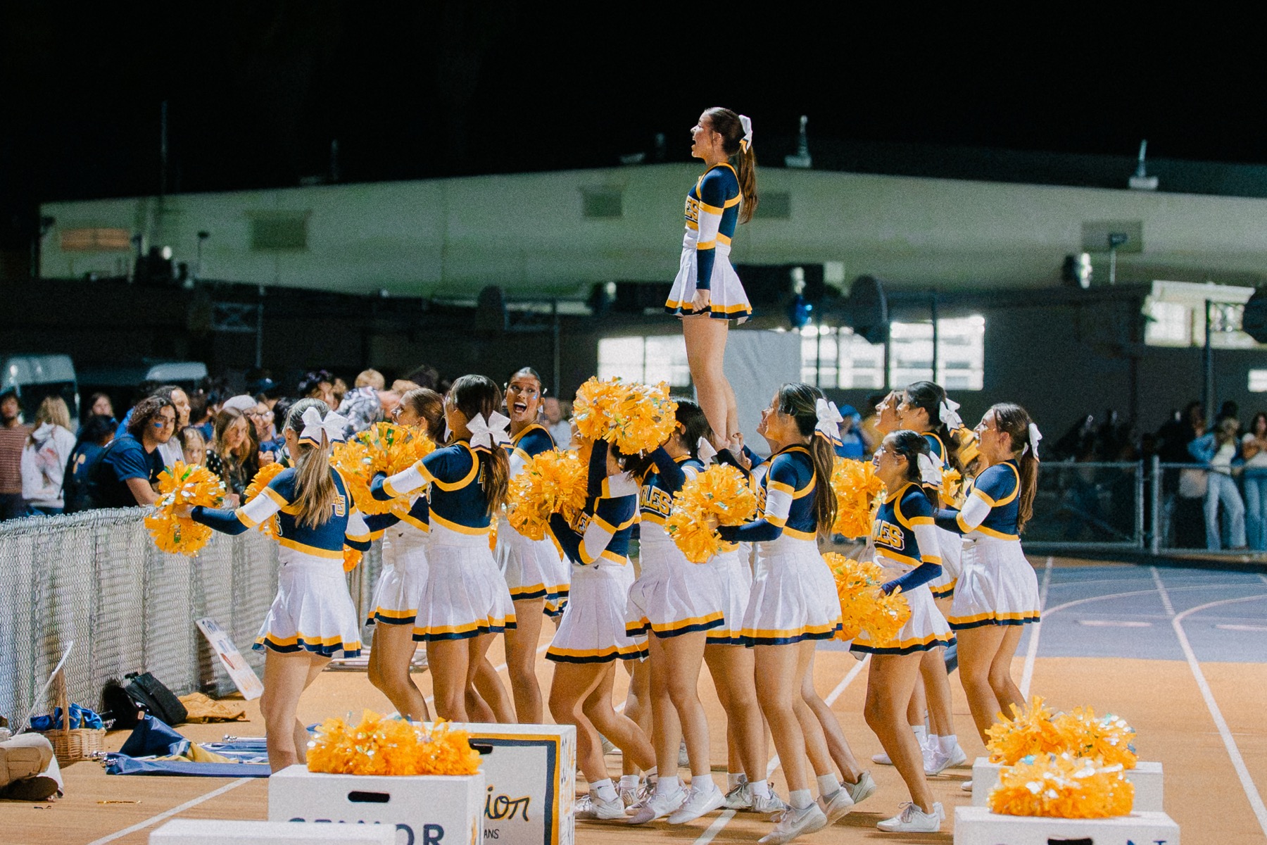 Arroyo Grande cheerleaders building a stunt under the stadium lights