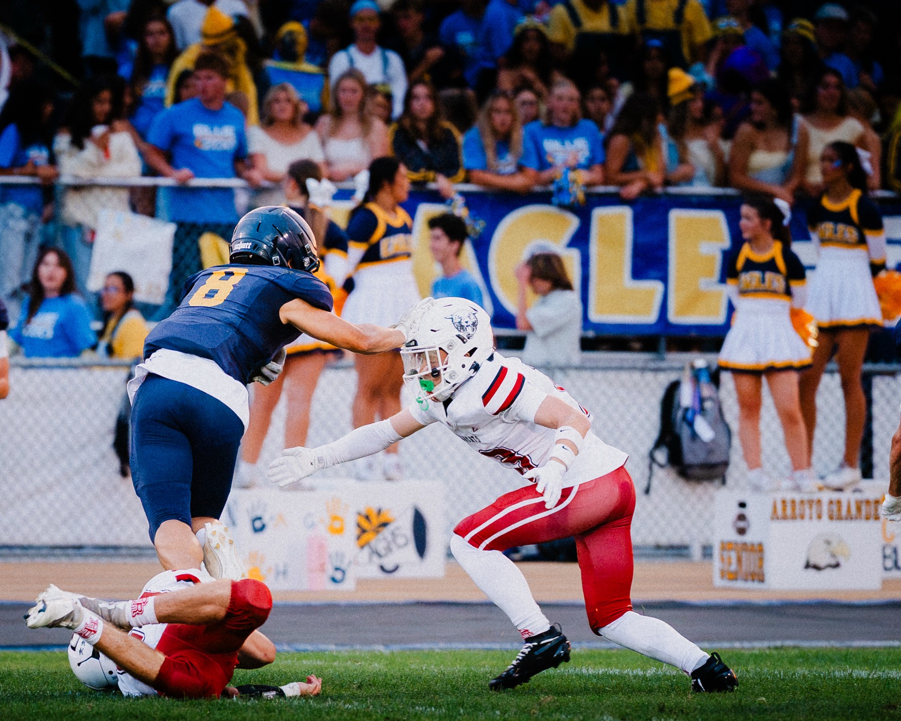 Arroyo Grande's defense closes in along the sideline as cheerleaders and the student section look on