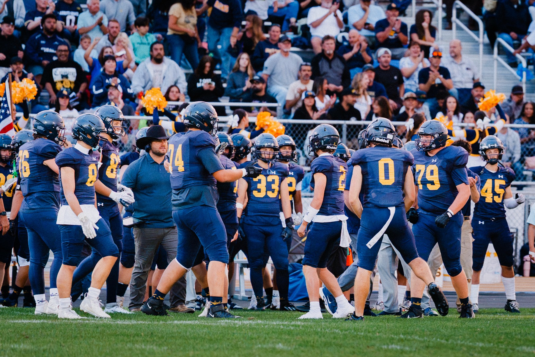 Arroyo Grande players and coaches huddle on the sideline during the home opener