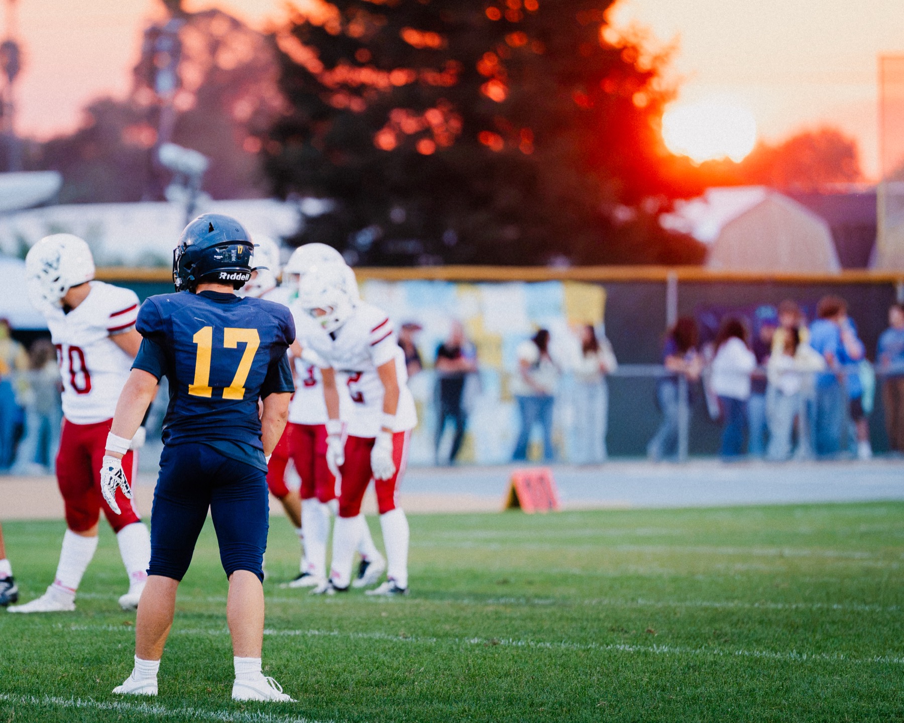 An Arroyo Grande player stands alone on the field as the sunset fades to dusk behind him