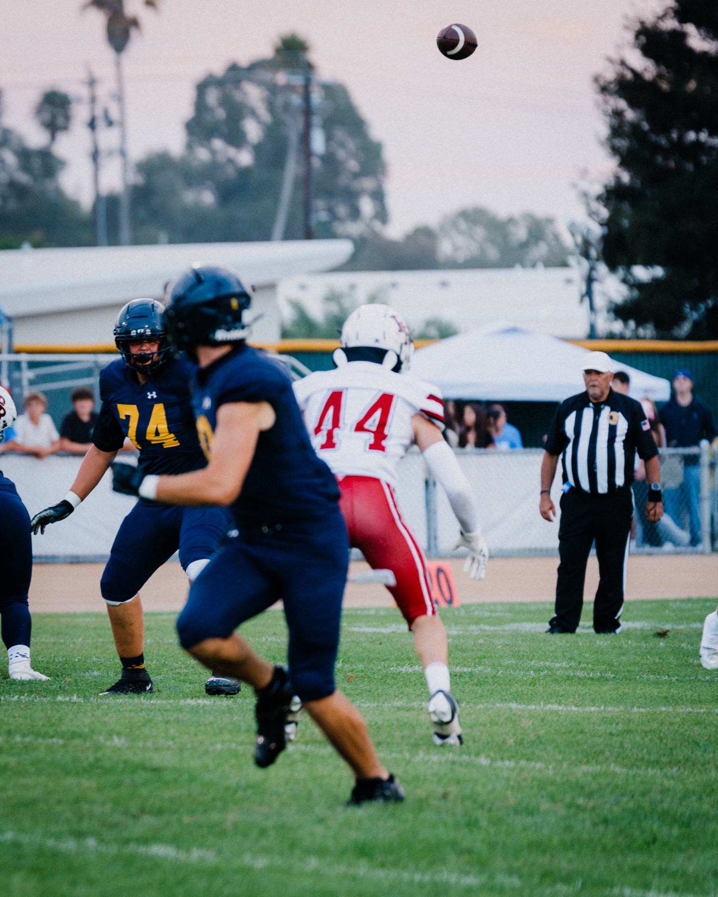 A football sails through the dusk sky as Arroyo Grande's offense runs a play