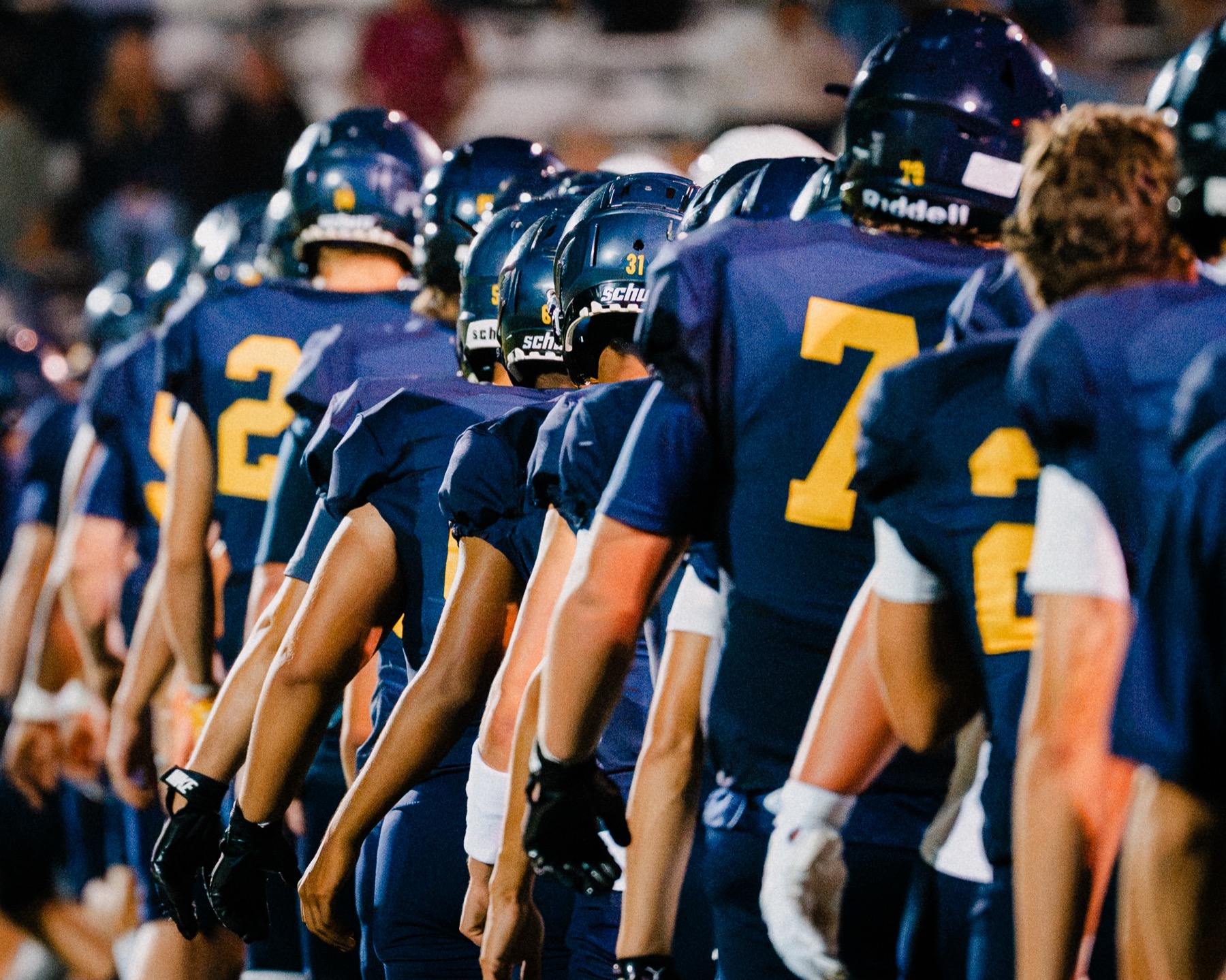 The Arroyo Grande football team lines up along the sideline under the lights