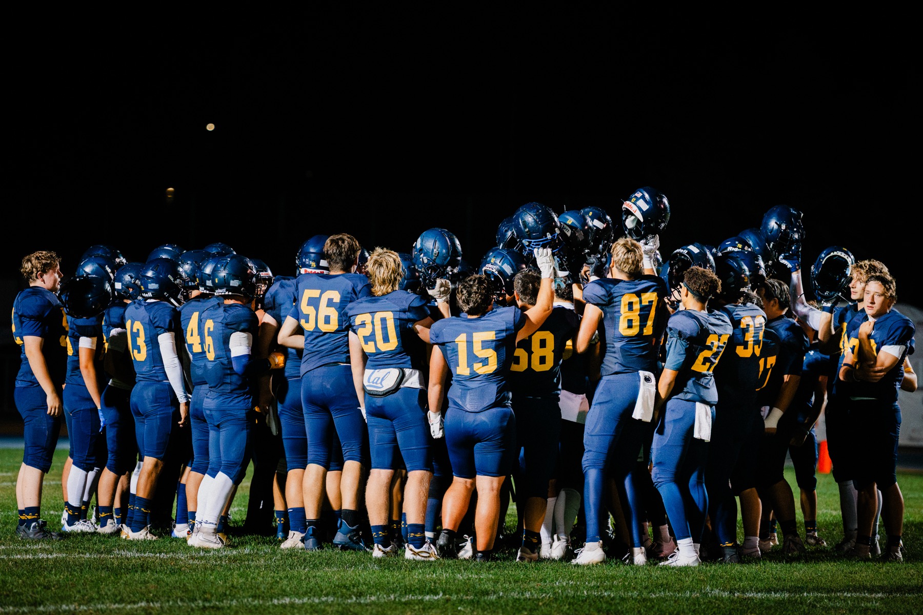 Arroyo Grande players walking the sideline together under the lights