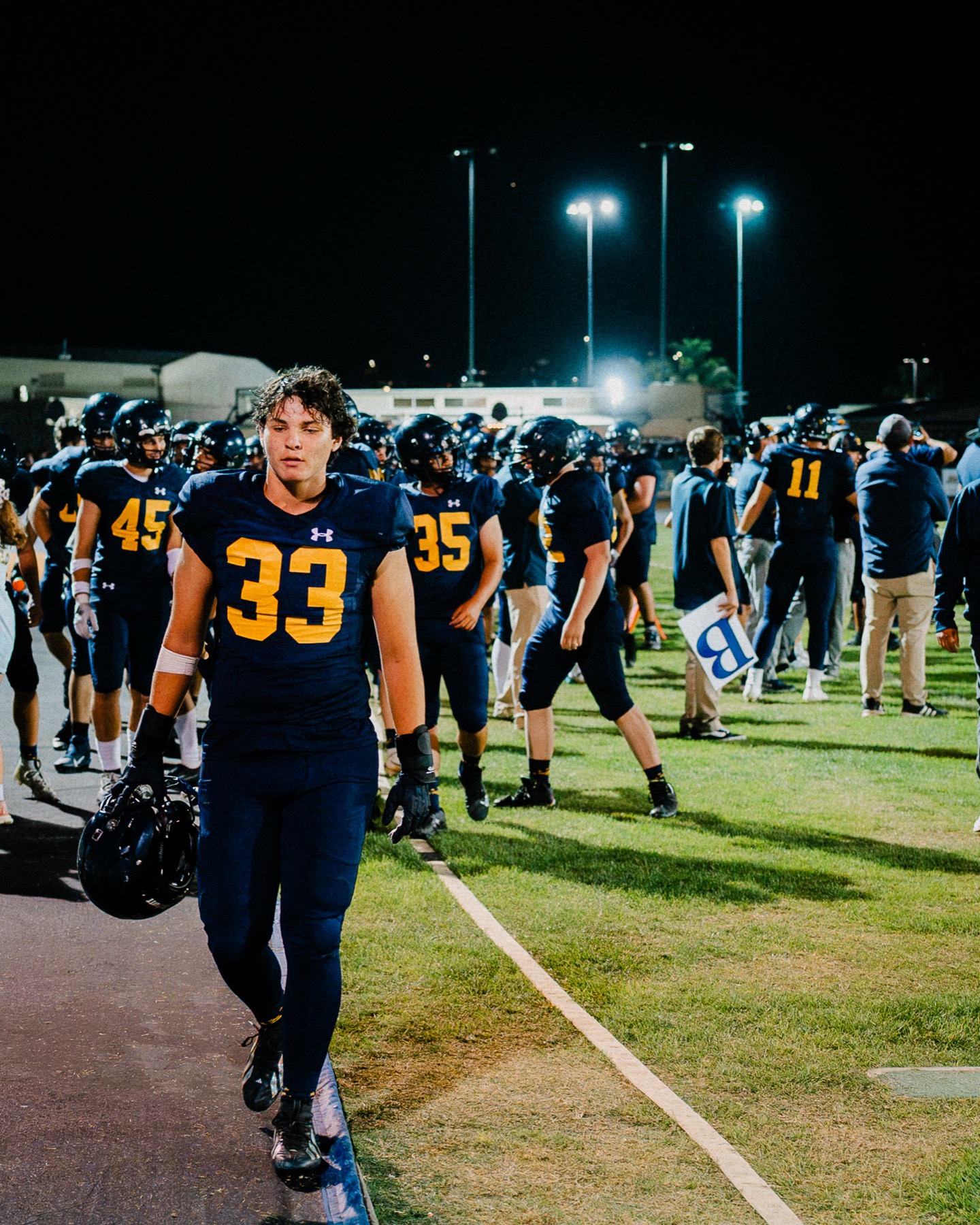 Arroyo Grande's team huddles together, helmets raised, during the home opener