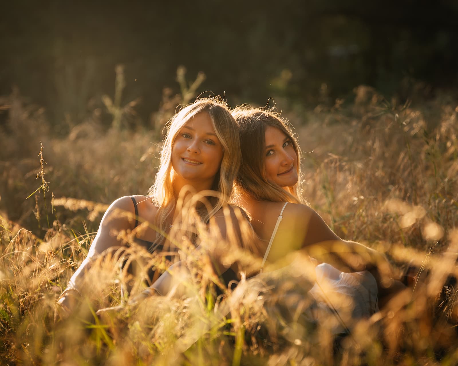 Two girls sitting in golden hour grass, Central Coast California