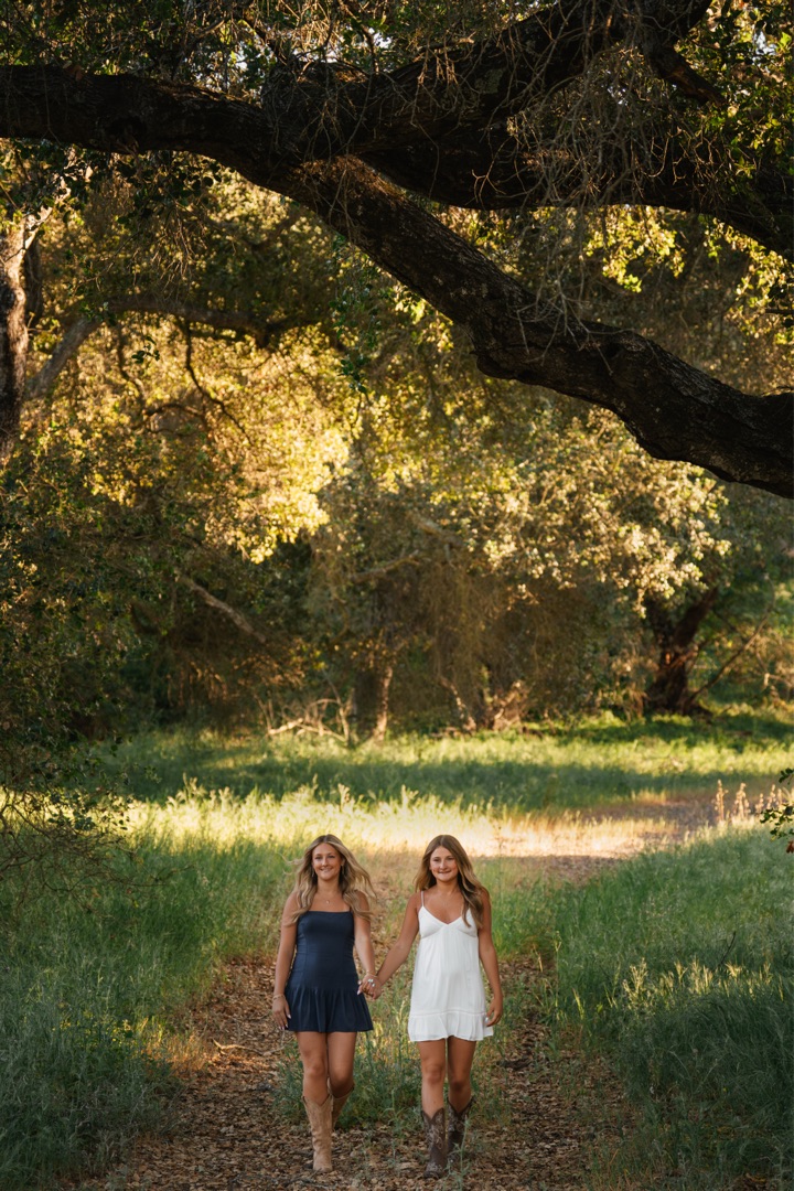 Two sisters walking through sunlit oak trees