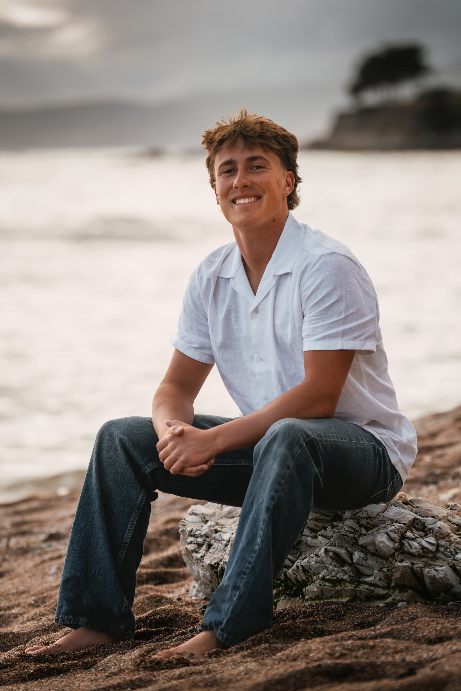 Senior boy sitting on coastal rocks, Central Coast California