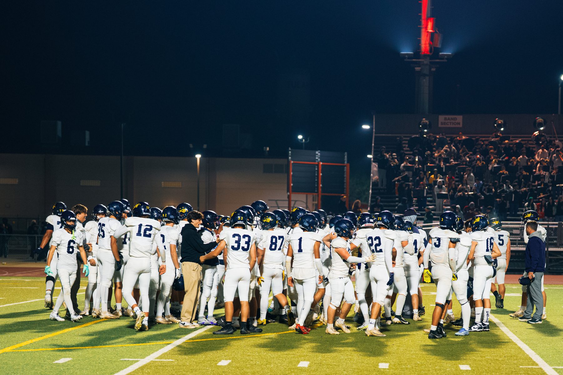 Football team huddled under goalpost at night