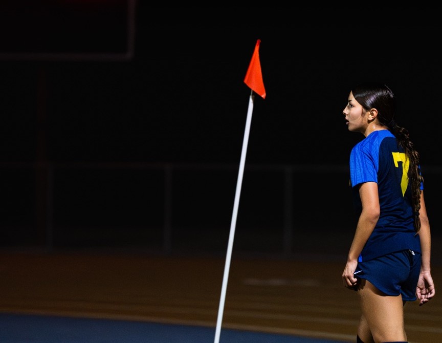 Female soccer player at night under stadium scoreboard