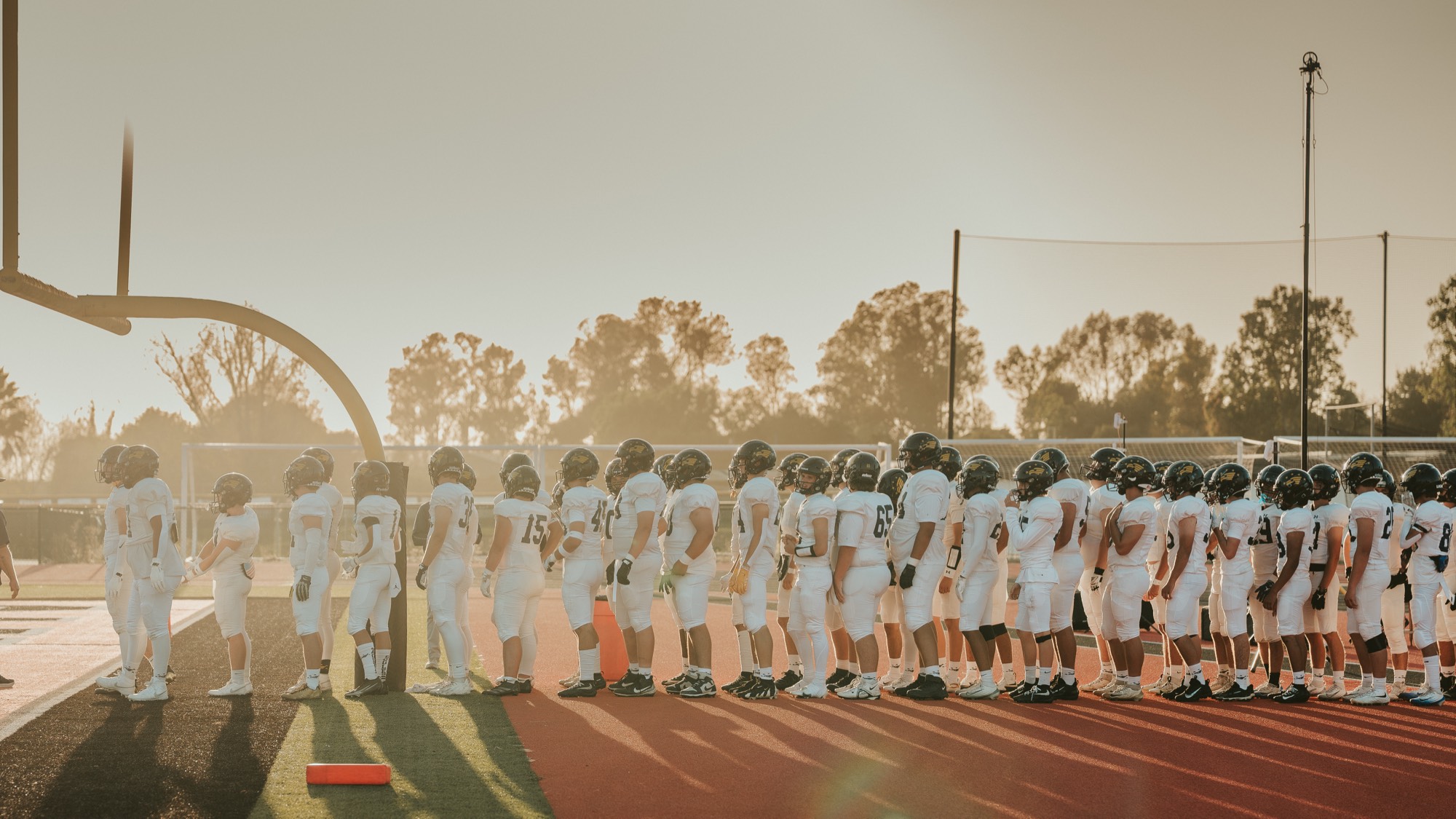 Arroyo Grande football team lined up on the track as the sun drops behind the stadium