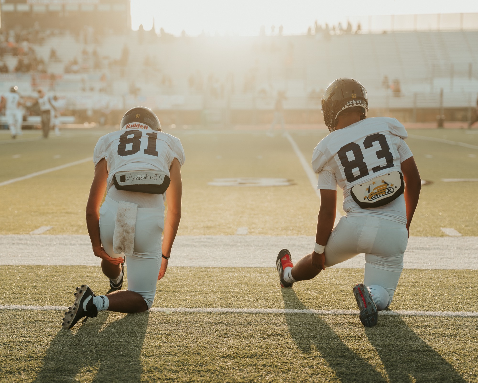 Arroyo Grande football players stretching on the sideline as the sun drops low
